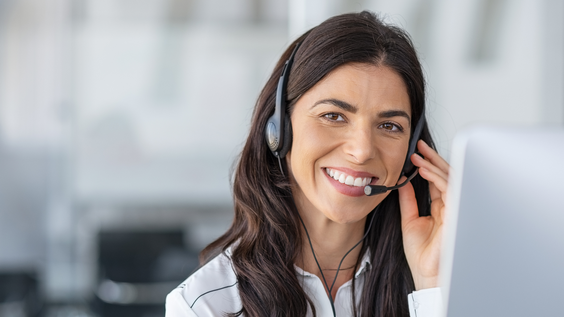 Person smiling while wearing a headset, working at a computer.