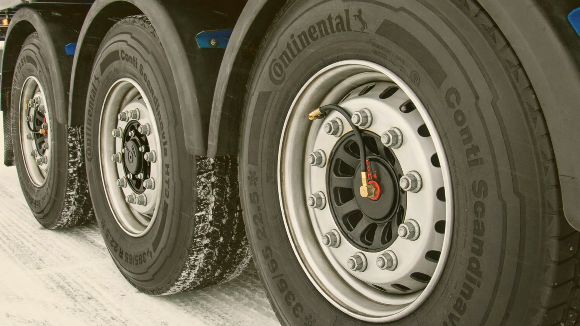 Close-up of trailer wheels with Continental tires by SAF-HOLLAND on a snowy road.